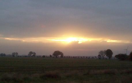 sun setting behind clouds with a silver lining